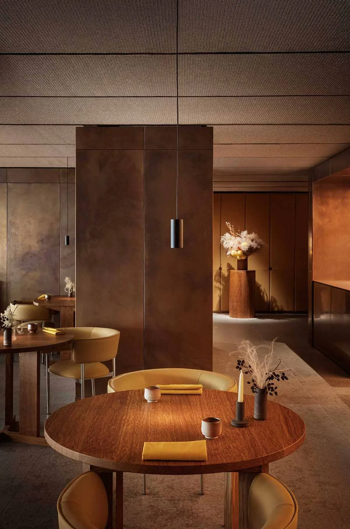 A modern industrial restaurant interior with metallic finishes, rounded tables, and minimalist decor.