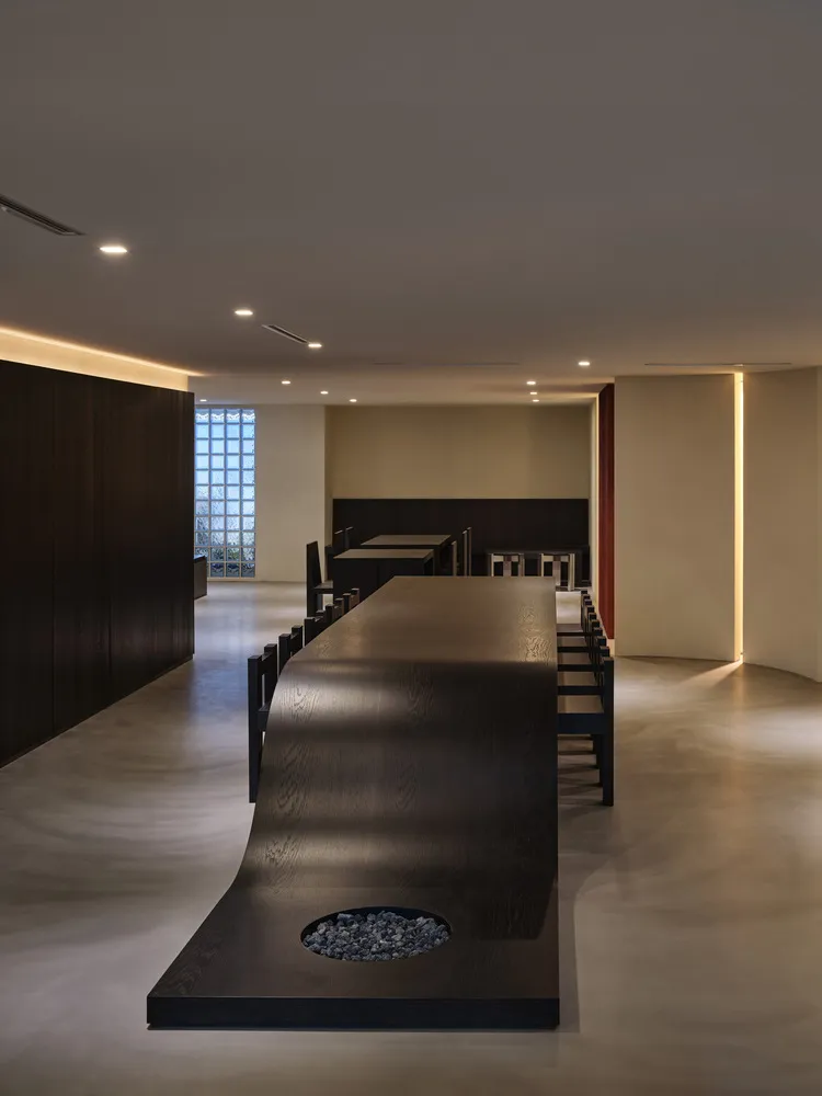 A modern industrial restaurant with dark wood furniture and concrete flooring.