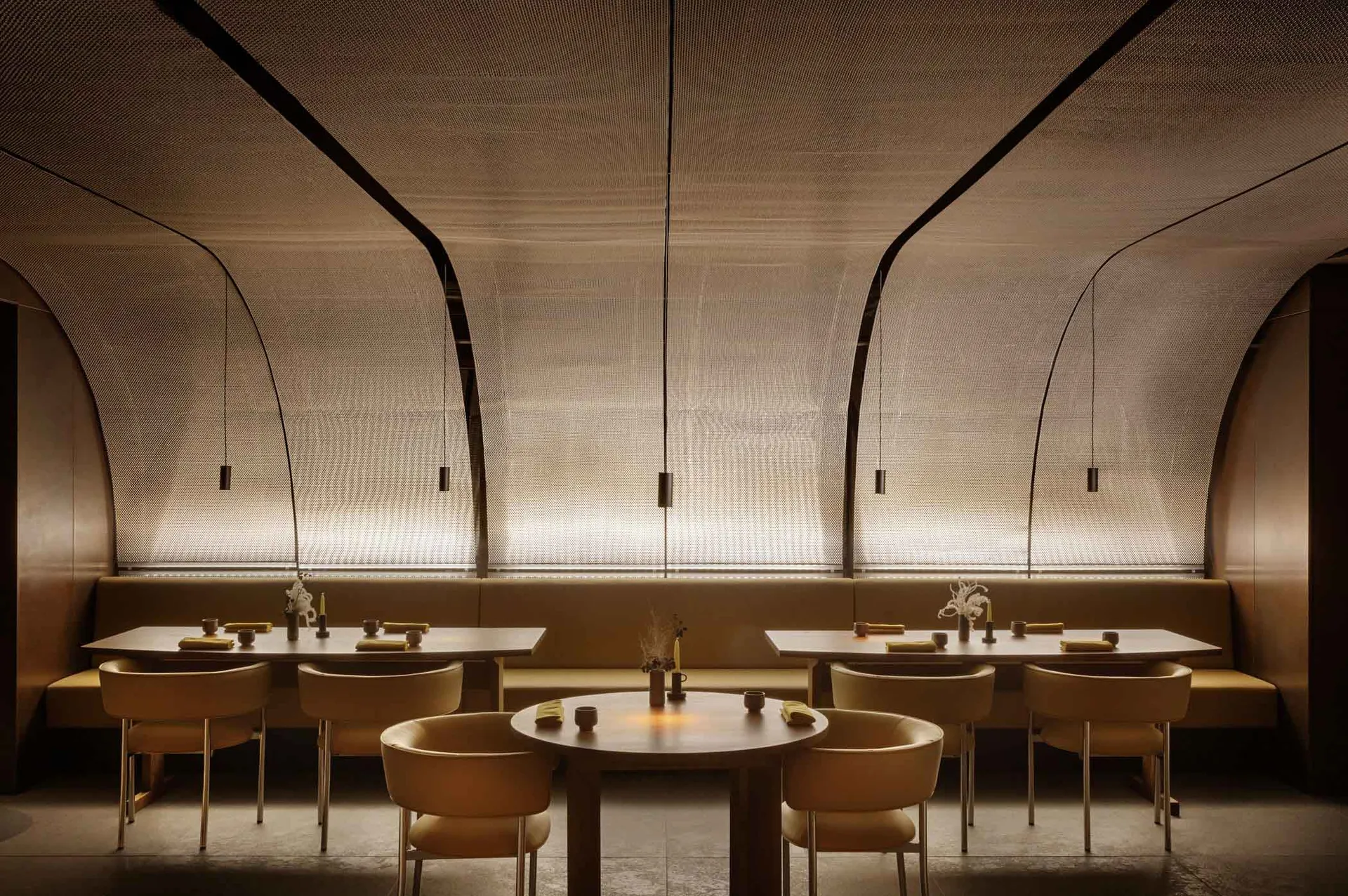 A modern restaurant interior featuring neutral-tones seating and tables adorned with minimalist decor.