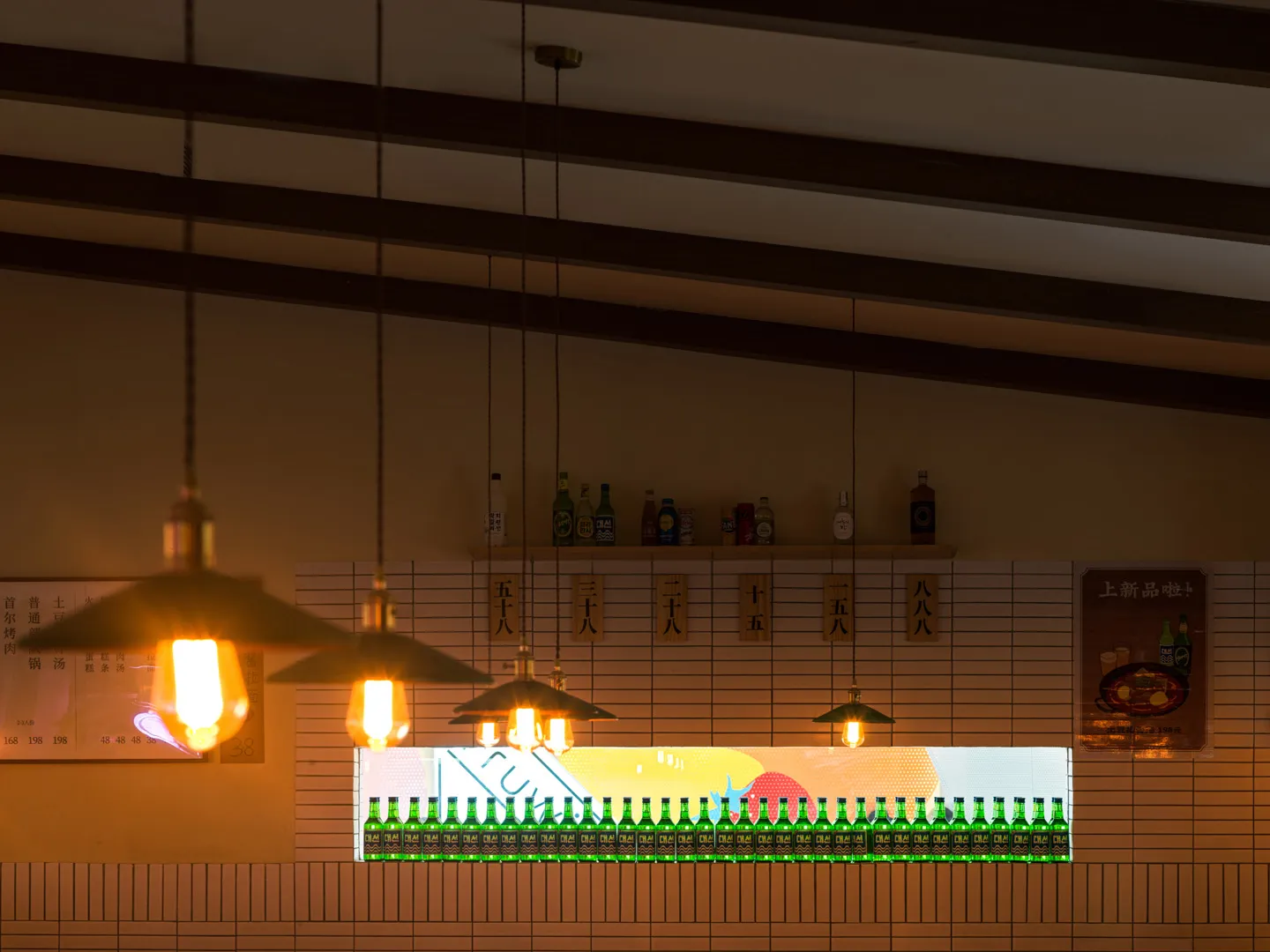 A brick-tiled bar counter with green bottles arranged in a row on the shelf.