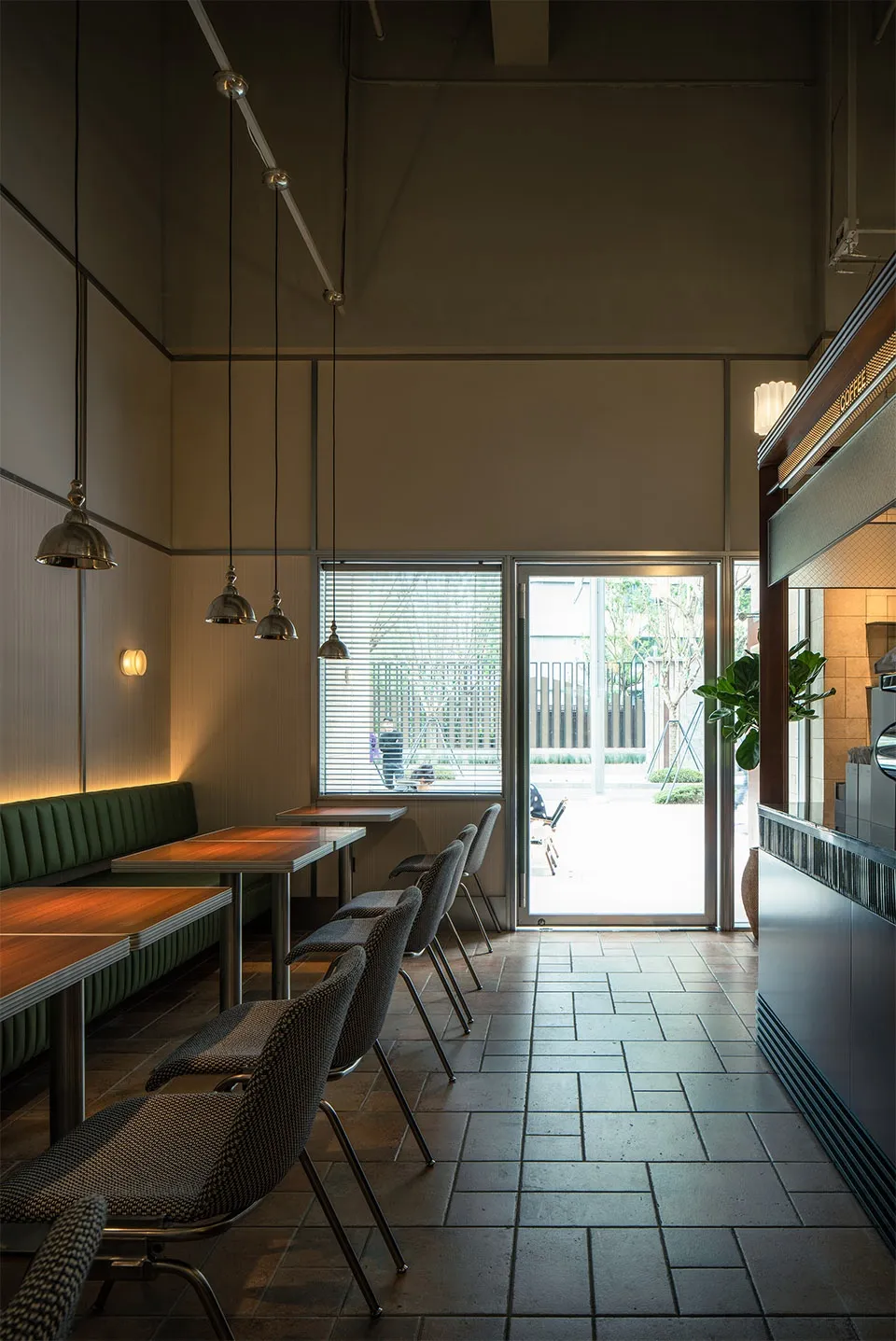 A modern cafe interior featuring wooden tables, metal chairs, and glass elements.