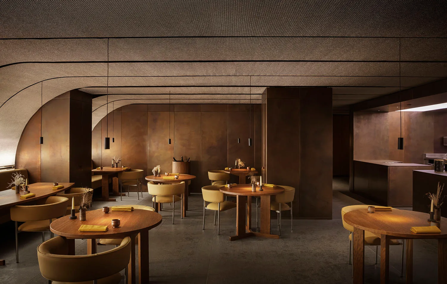 Modern restaurant interior with round wooden tables, yellow cushions, and minimalistic decor.