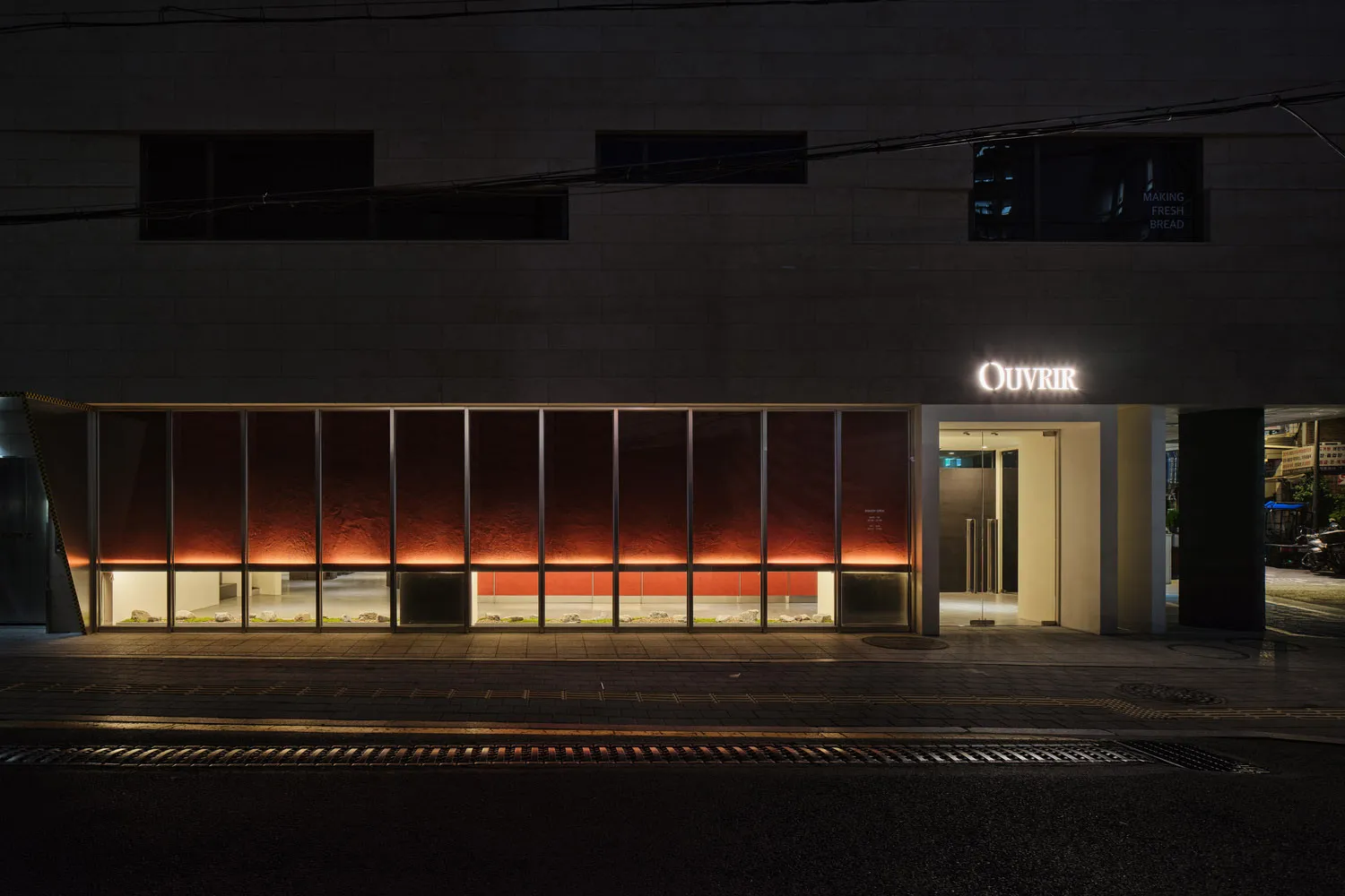 A modern retail storefront with illuminated glass windows at night.