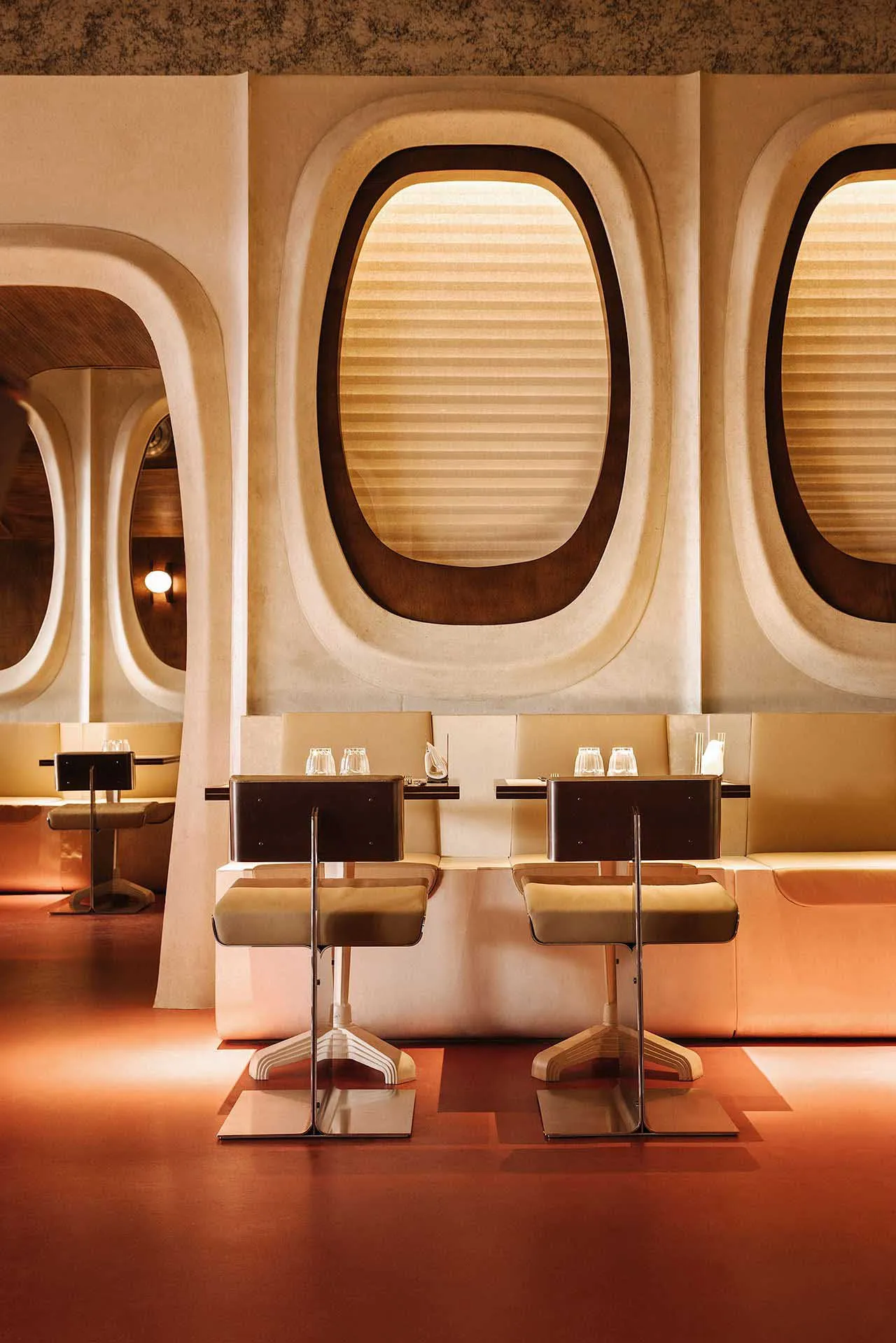 Modern restaurant interior with sleek booth seating and large windows.