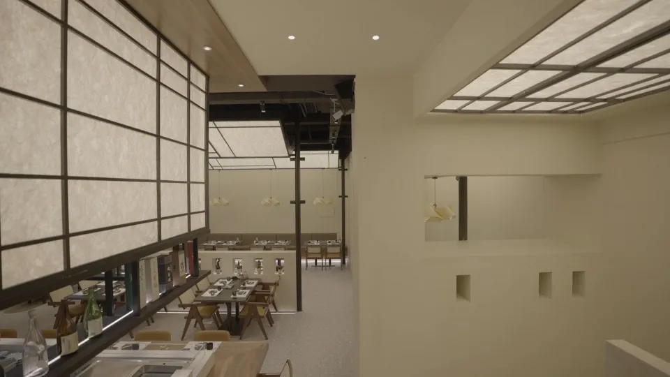 A modern restaurant interior with minimalist design, showcasing sleek white walls and lighting.