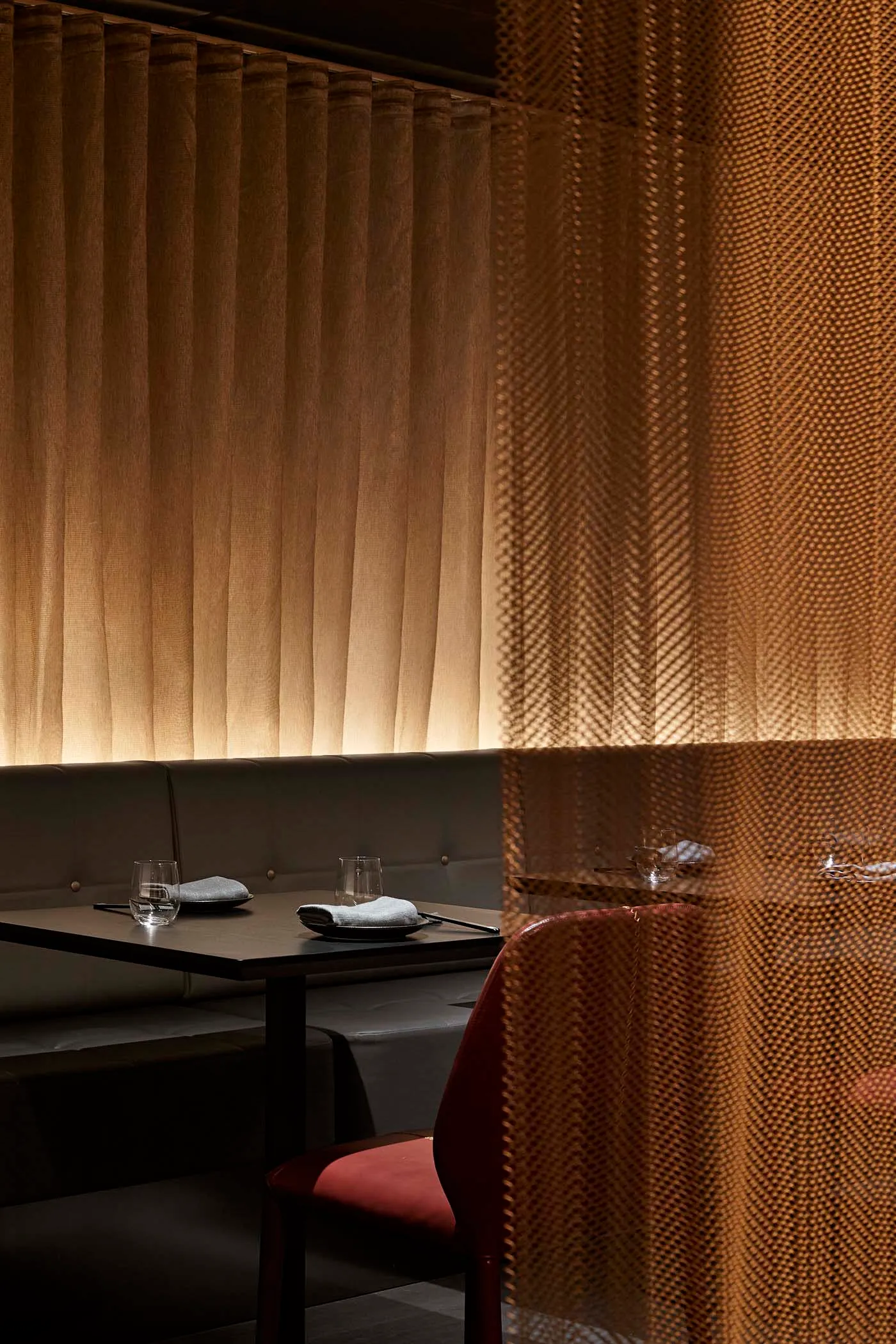 A modern restaurant interior featuring textured fabric curtains and a booth-style seating arrangement.