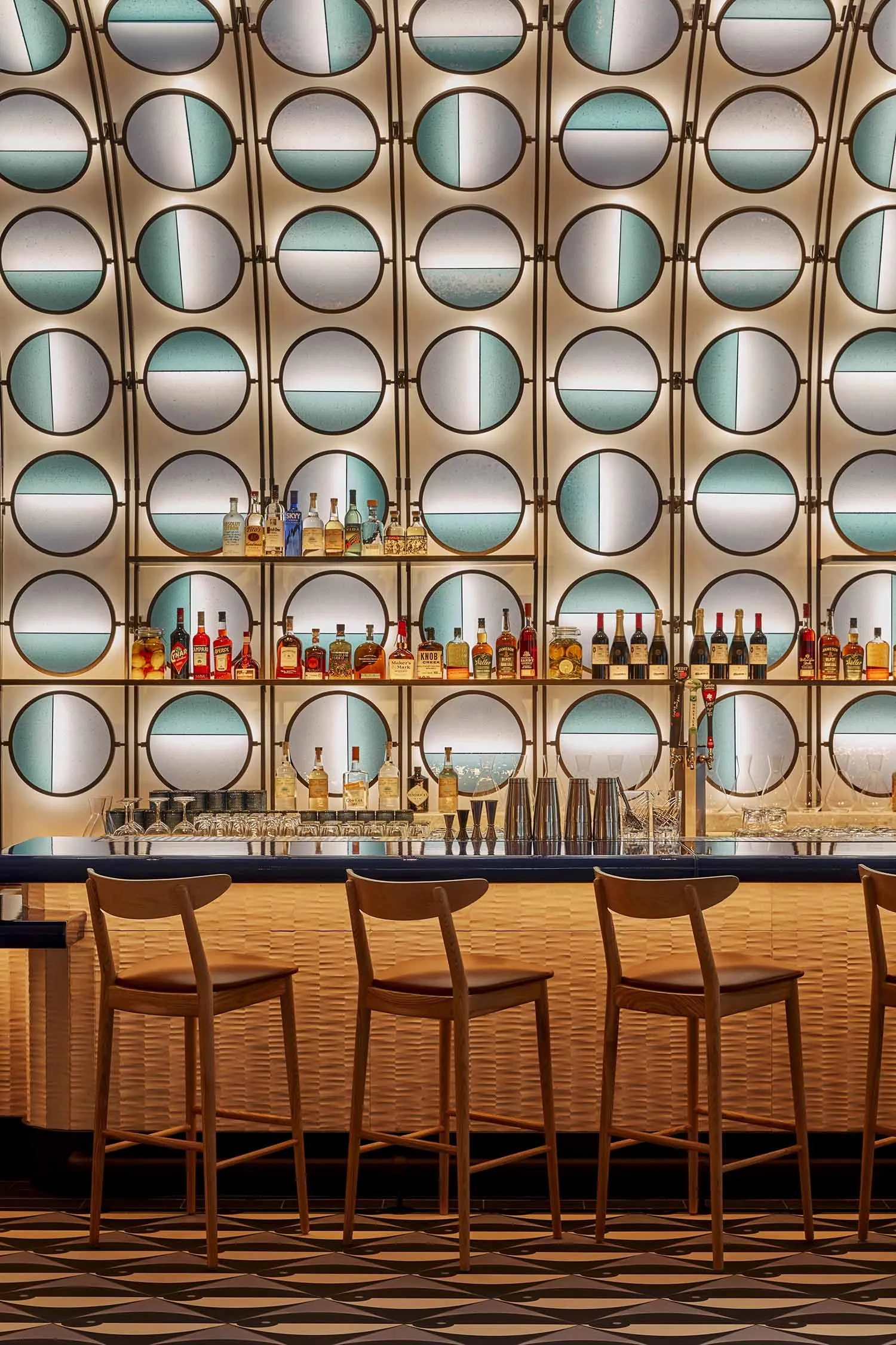 A modern bar interior featuring a stylish bar counter with glazed tiles and woven wood accents.