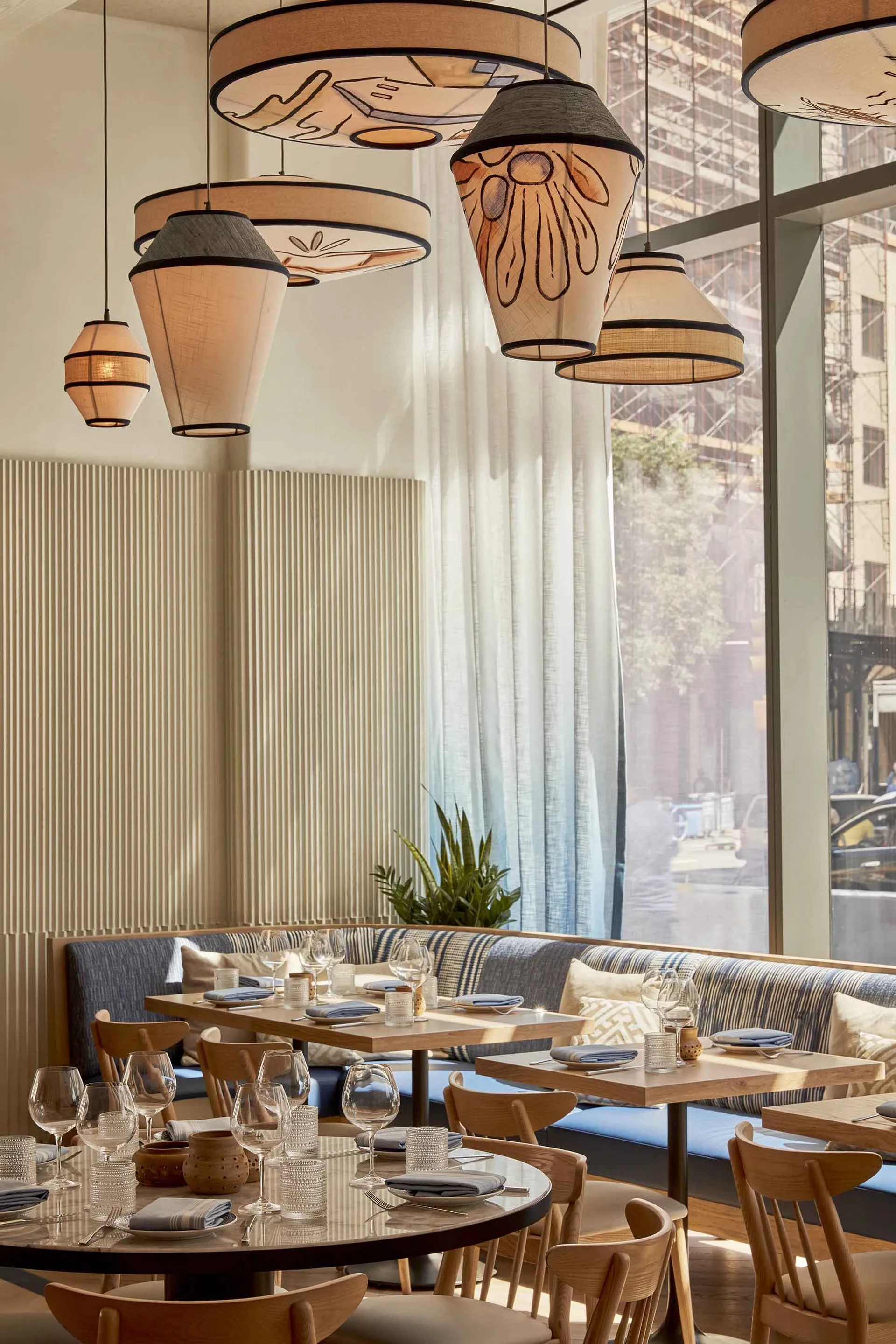 Sunny cafe interior with modern textile lighting and wooden furniture.