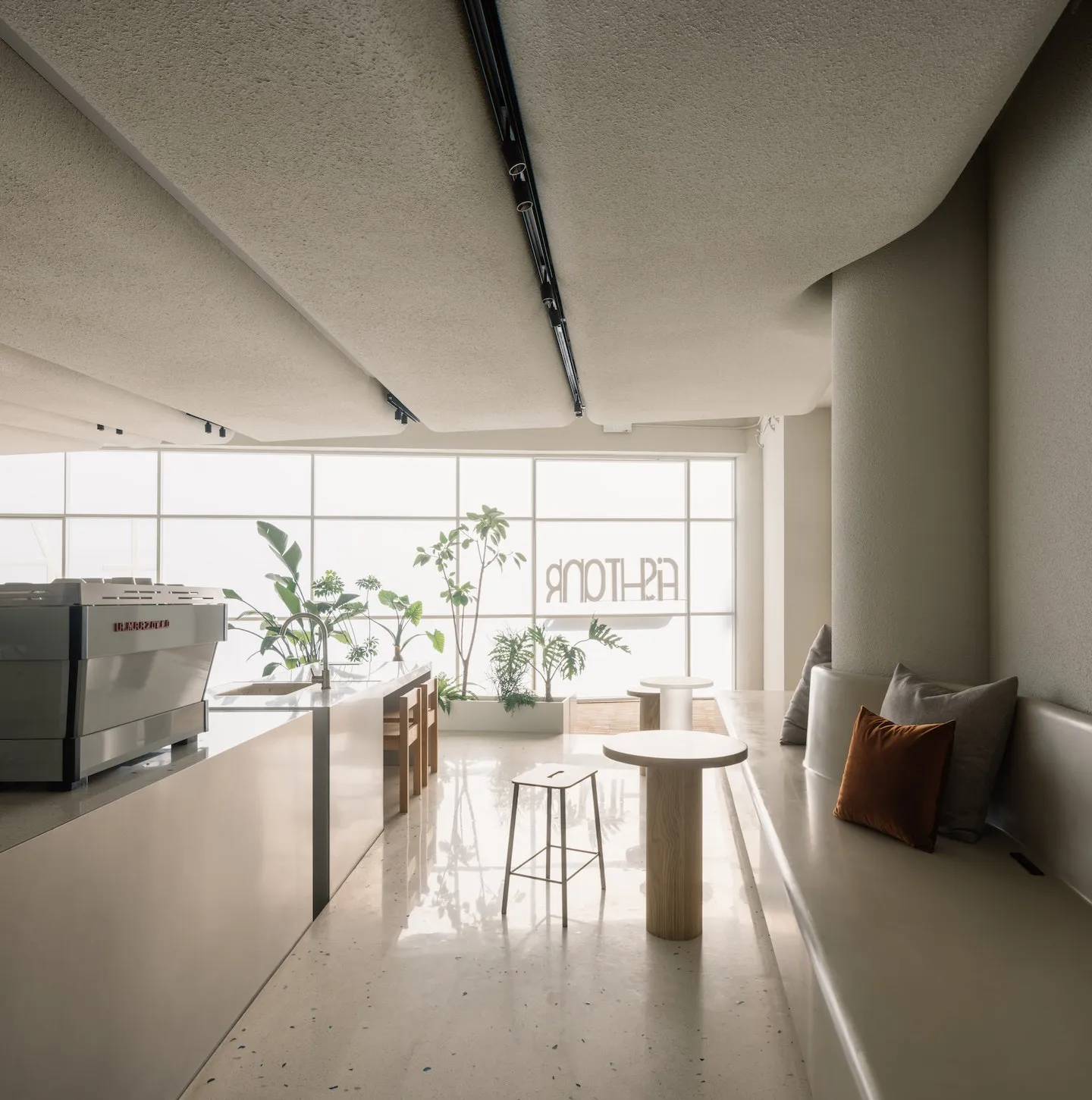 A modern coffee shop with a terrazzo floor and concrete walls.