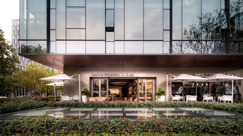Modern coffee shop facade with glass curtain wall and outdoor seating area