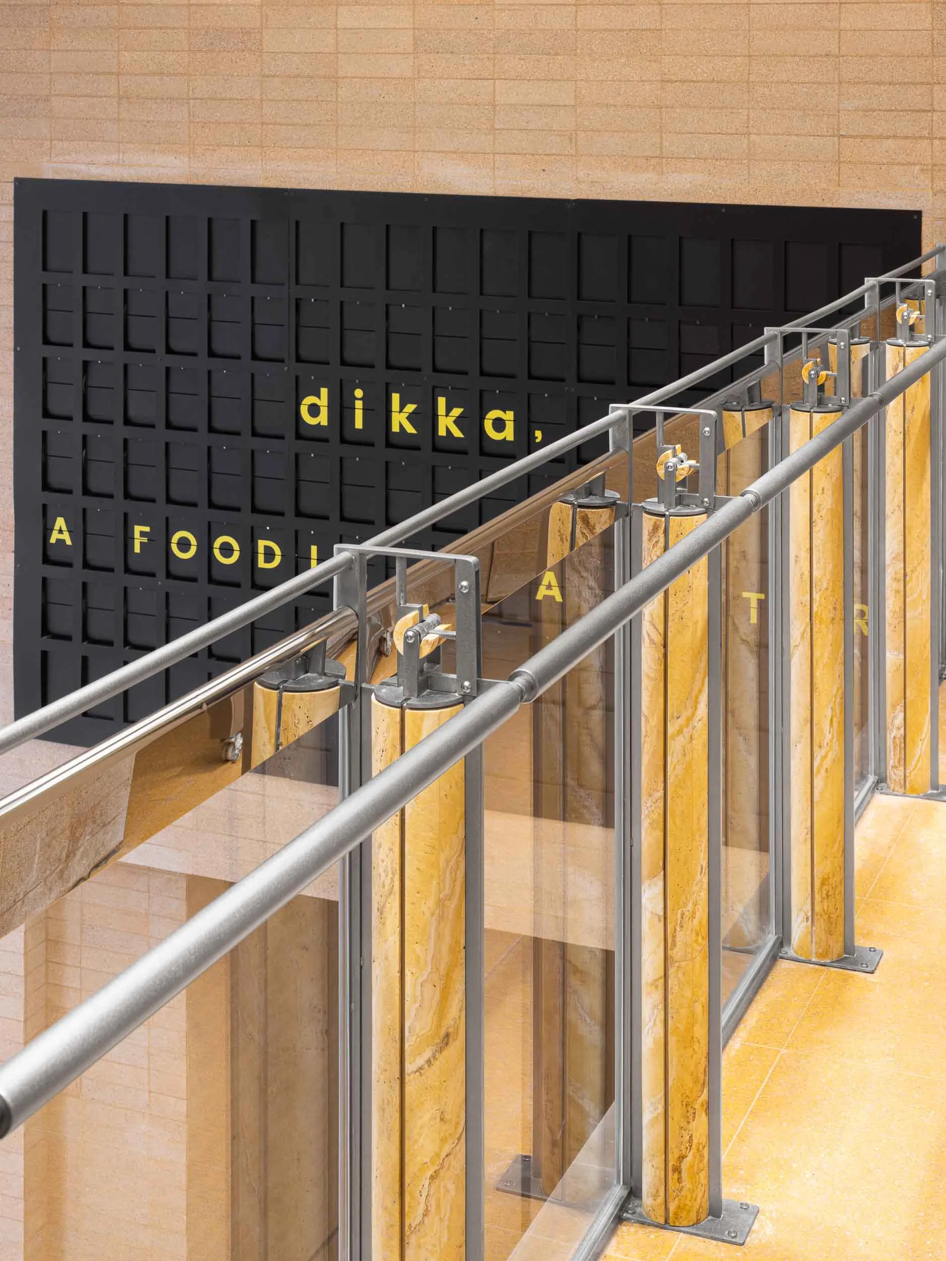 Modern industrial staircase with steel railing and marble pillars and floor.
