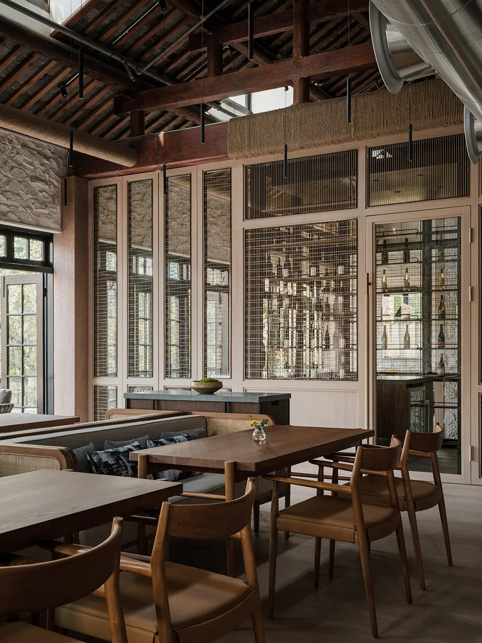 Modern restaurant interior with wooden tables, chairs, and exposed wooden beams and rafters.