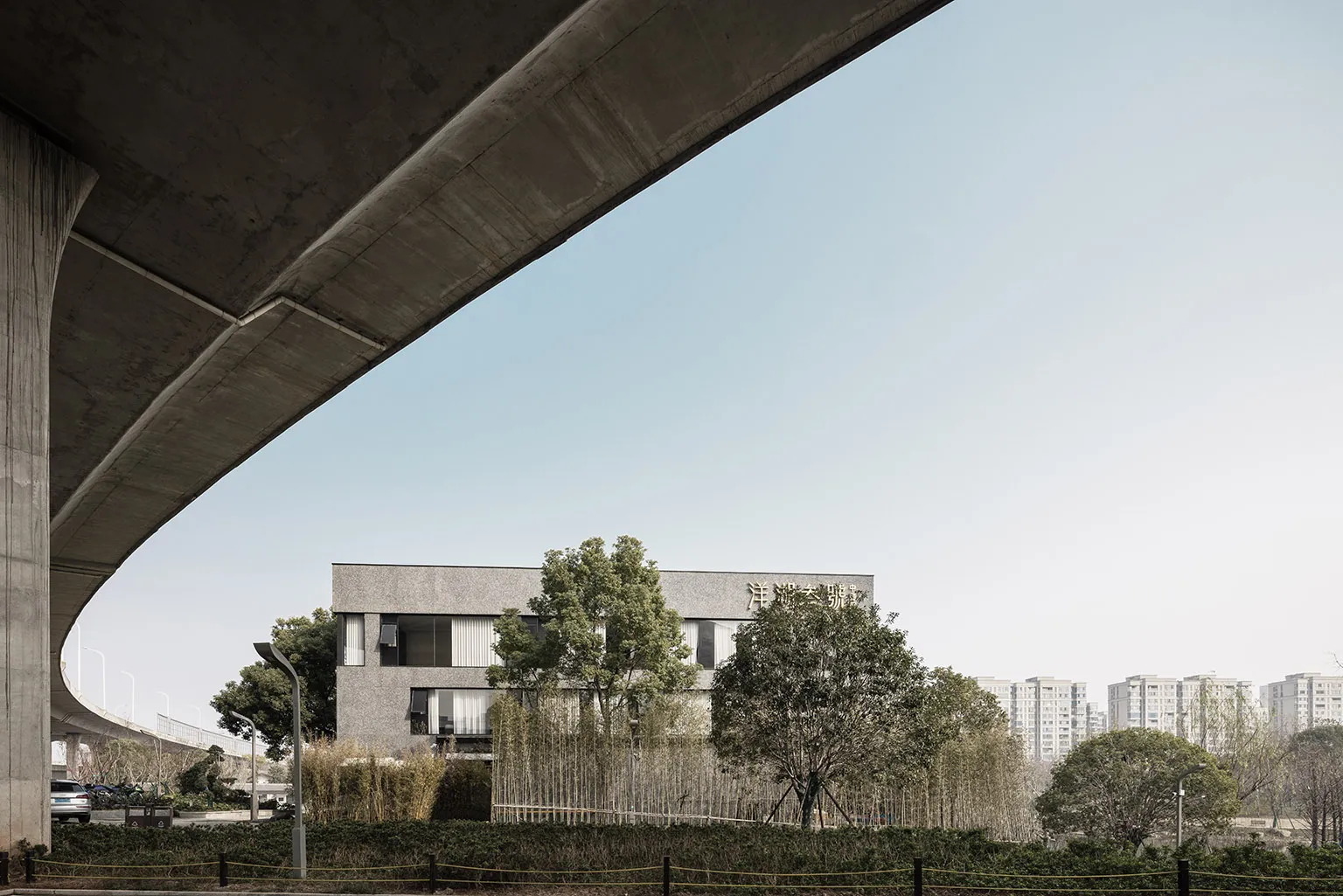 Modern office building with concrete facade and greenery in the foreground.