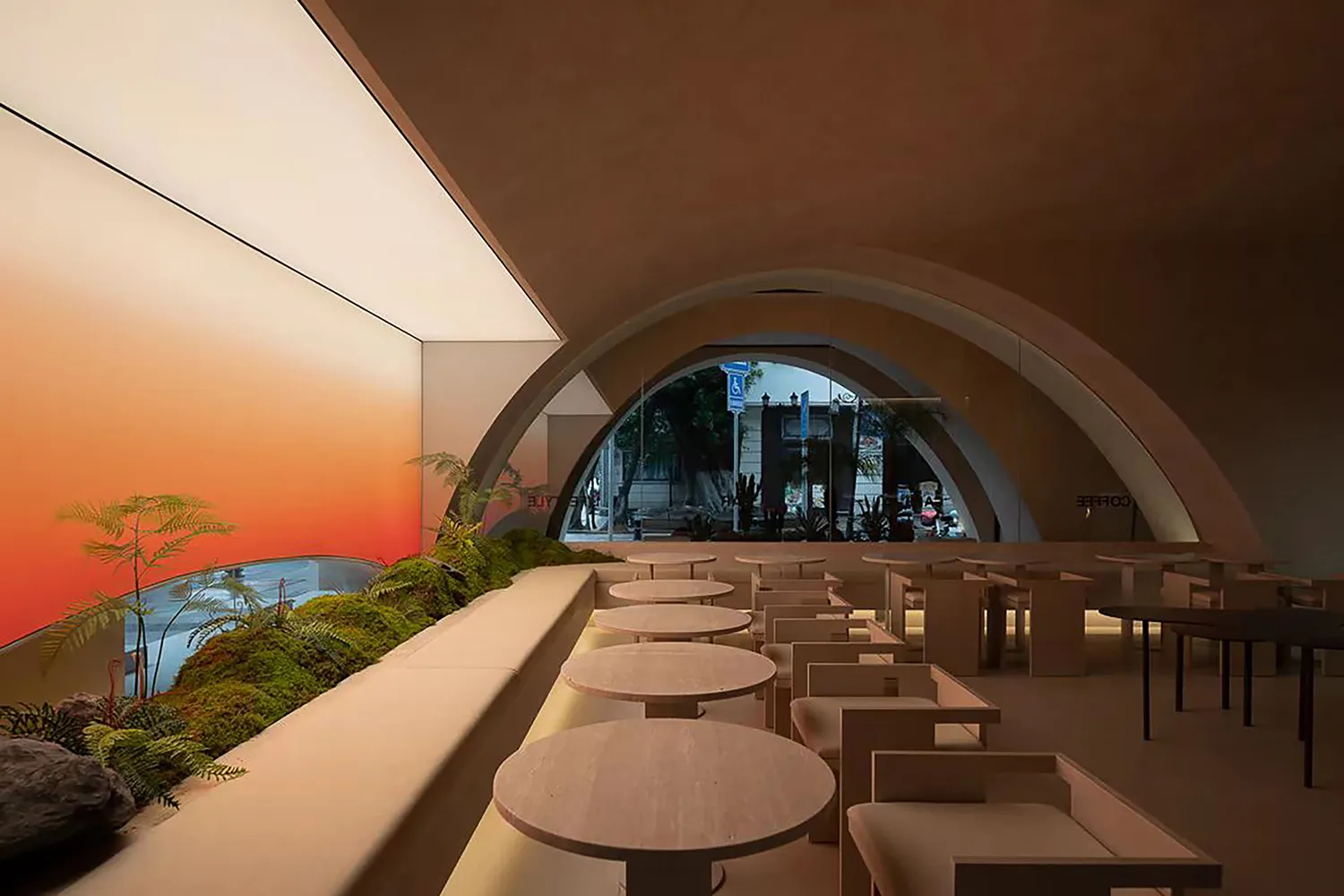 A modern restaurant interior with concrete texture walls and arches, featuring round tables and a living green wall.