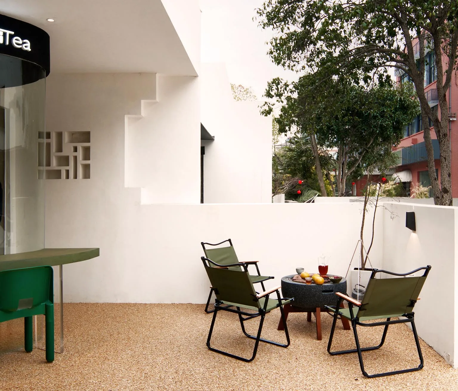 Minimalist outdoor lounge area with green seating and concrete patio.