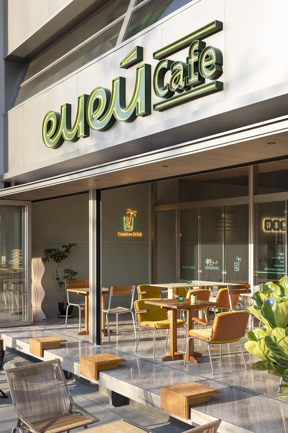 Outdoor seating area of a modern cafe with white marble ground and green signage.