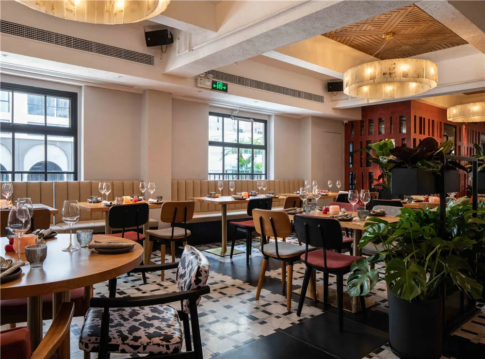 Modernly designed restaurant space with a mix of materials like wooden tables, upholstered chairs, and decorative plants.