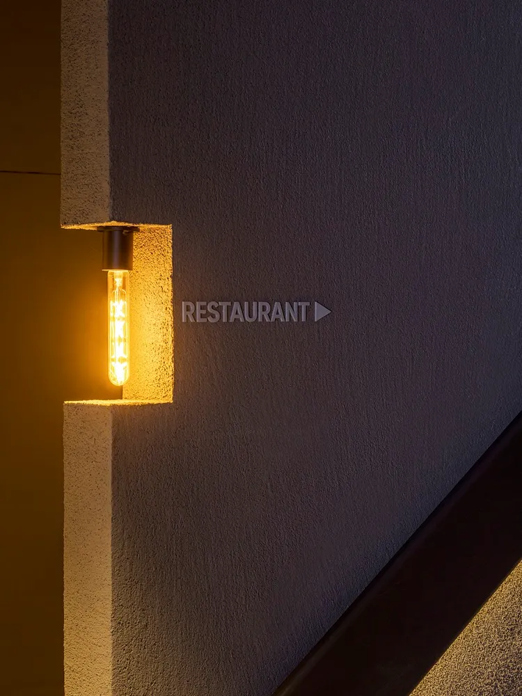 Modern concrete wall with a light bulb and directional sign for a restaurant