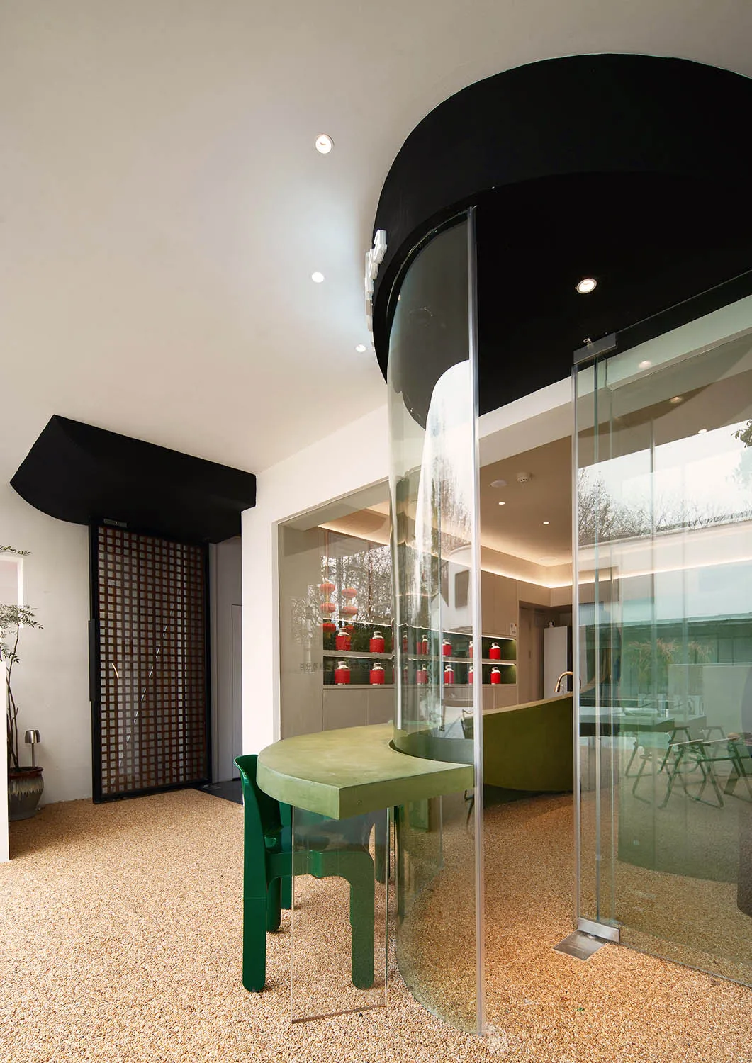 Modern restaurant interior with glass walls and green accents.