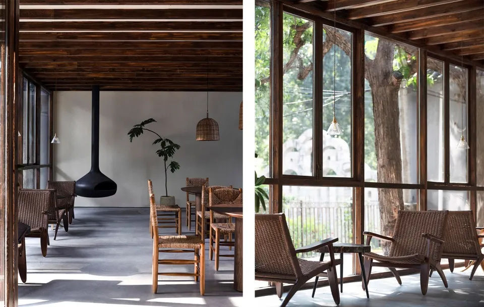 A minimalist cafe interior featuring wooden furnishings and a hanging fireplace.