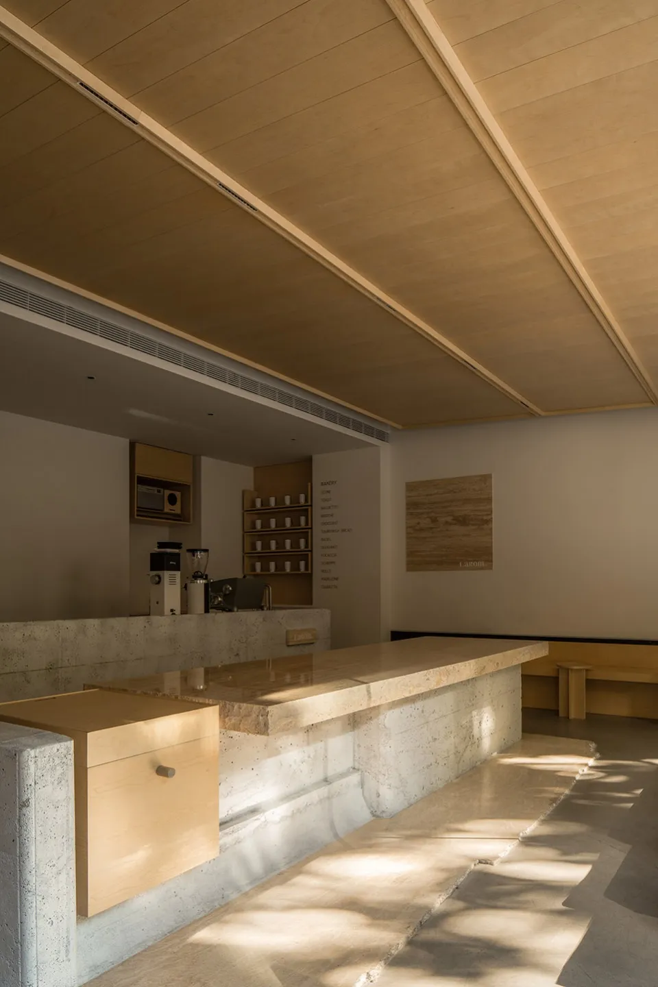 Interior view of a minimalist modern coffee shop featuring marble countertops and concrete finishes.