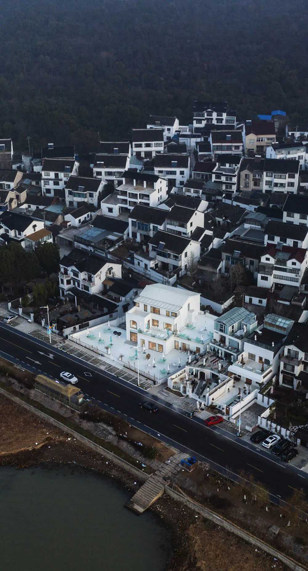 Aerial view of a modern village featuring white houses with black roofs.