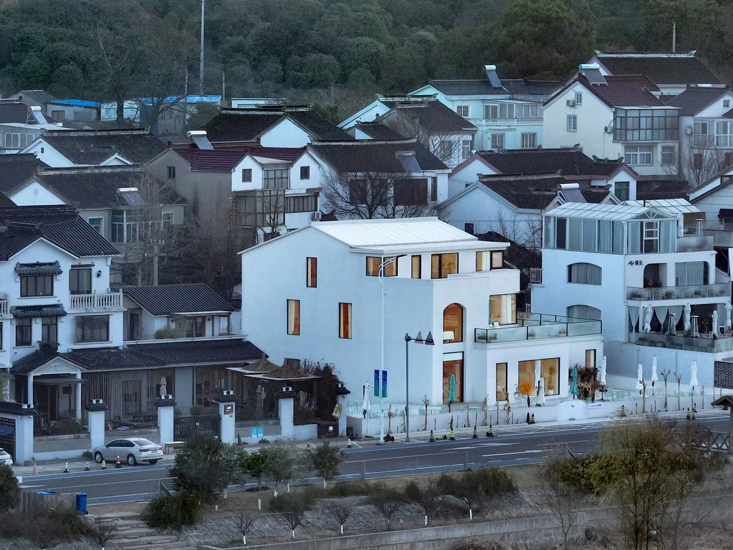 A modern white house with multiple levels and large windows.