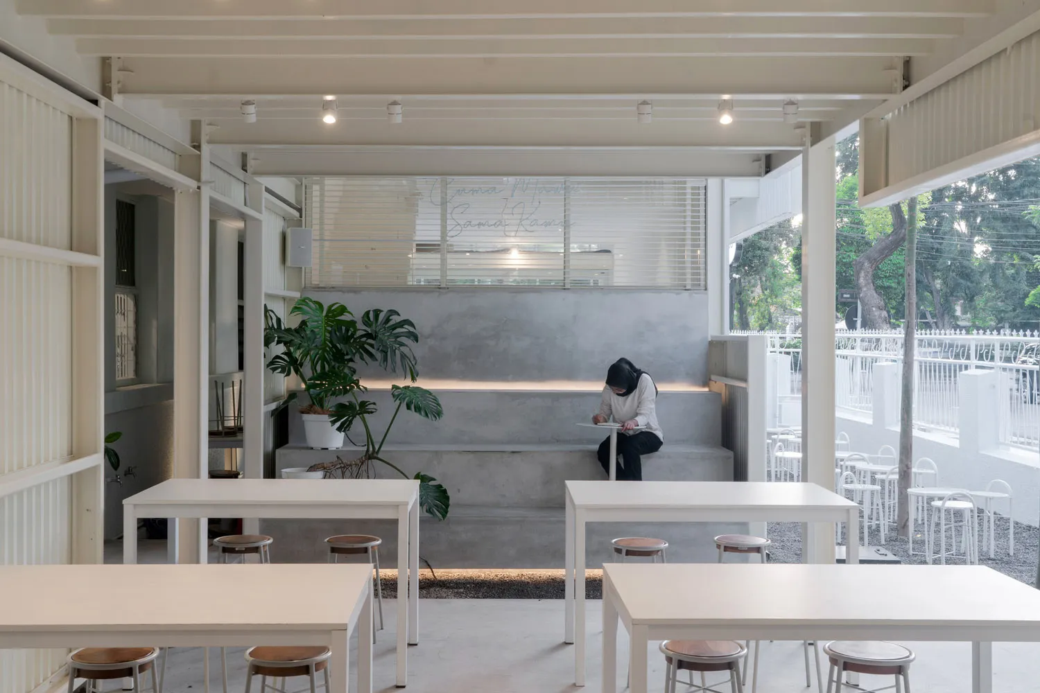 A minimalist cafe interior featuring concrete walls and wooden furniture.