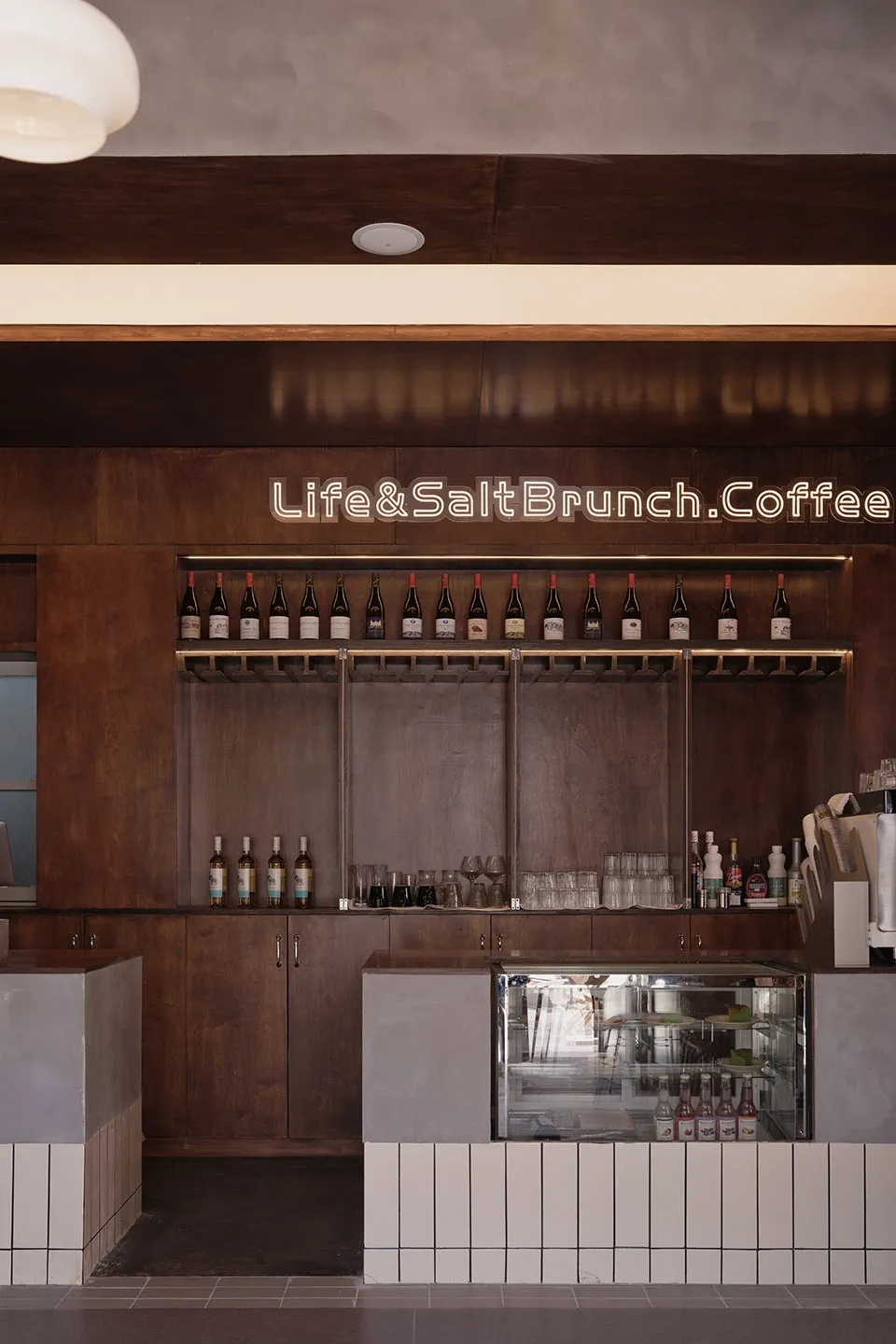 Modern coffee shop interior showcasing an elegant wooden counter with bottles of wine lined up on the shelf.
