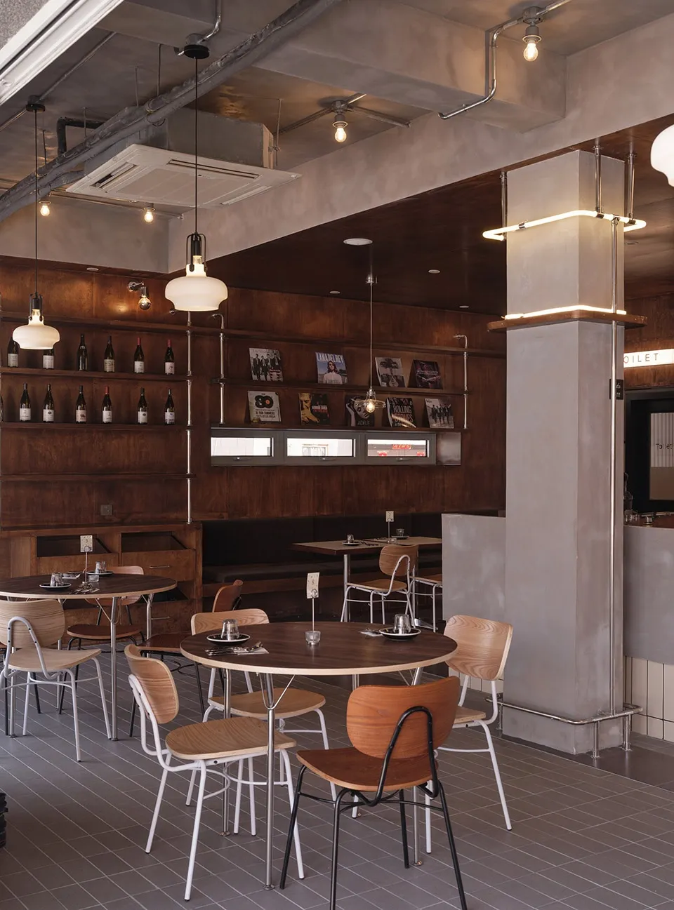 Industrial-style restaurant interior with wooden tables, metal chairs, and concrete walls.