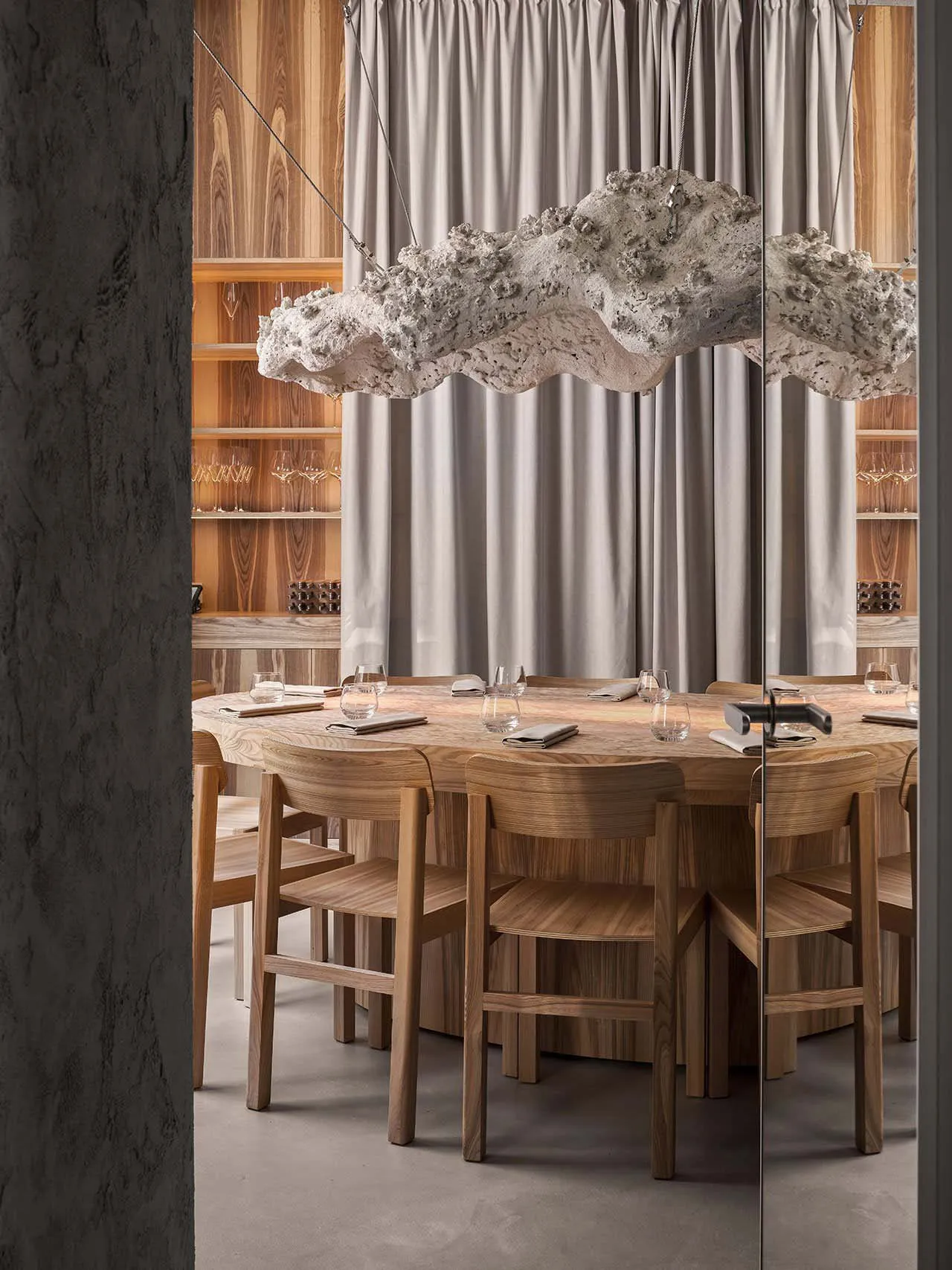 Circular wooden table with minimalistic decor and lighting in a modern restaurant setting.