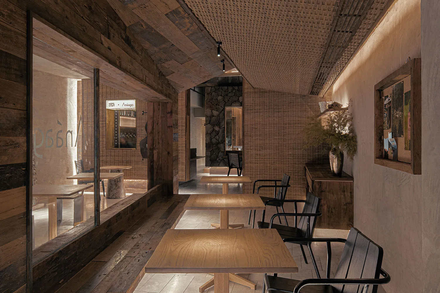 A modern restaurant interior featuring wooden tables, chairs, and ceiling panels.