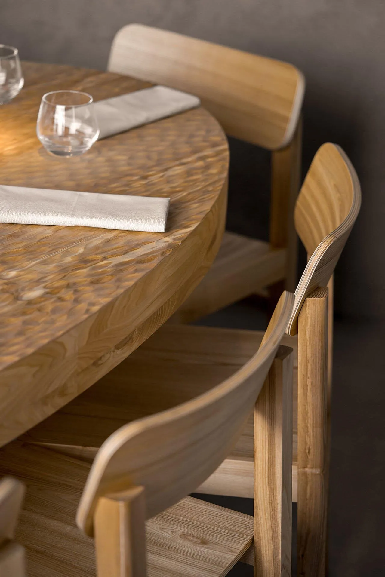 A modern restaurant interior with wooden furniture and a polished wooden table