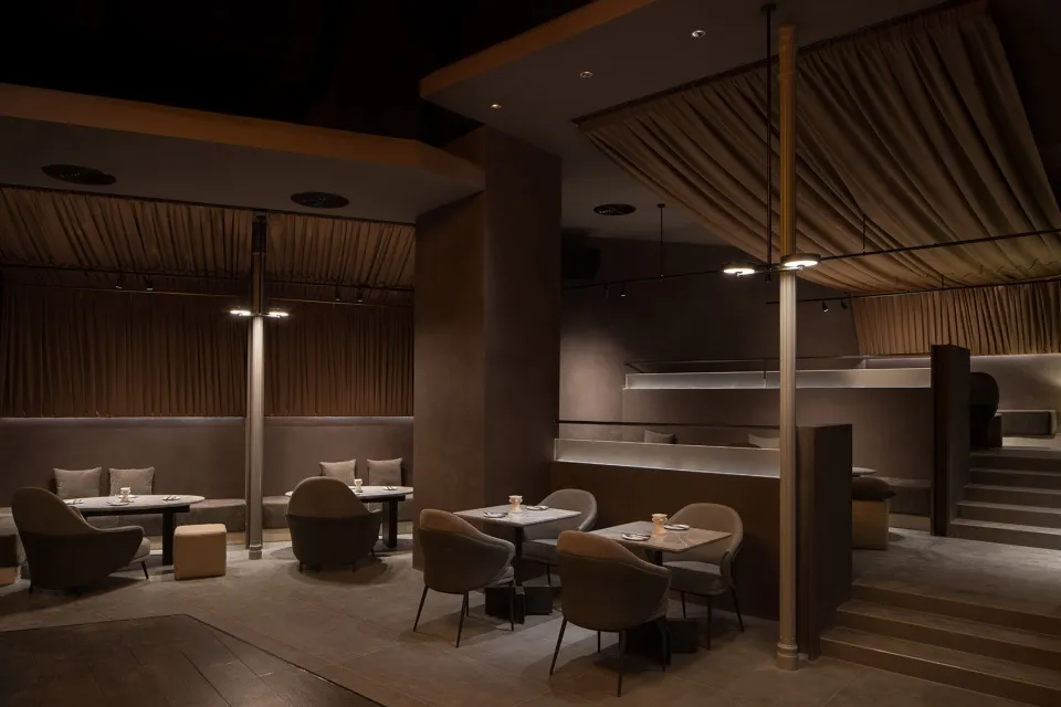 A modern restaurant interior with dark-toned materials and contemporary design elements.