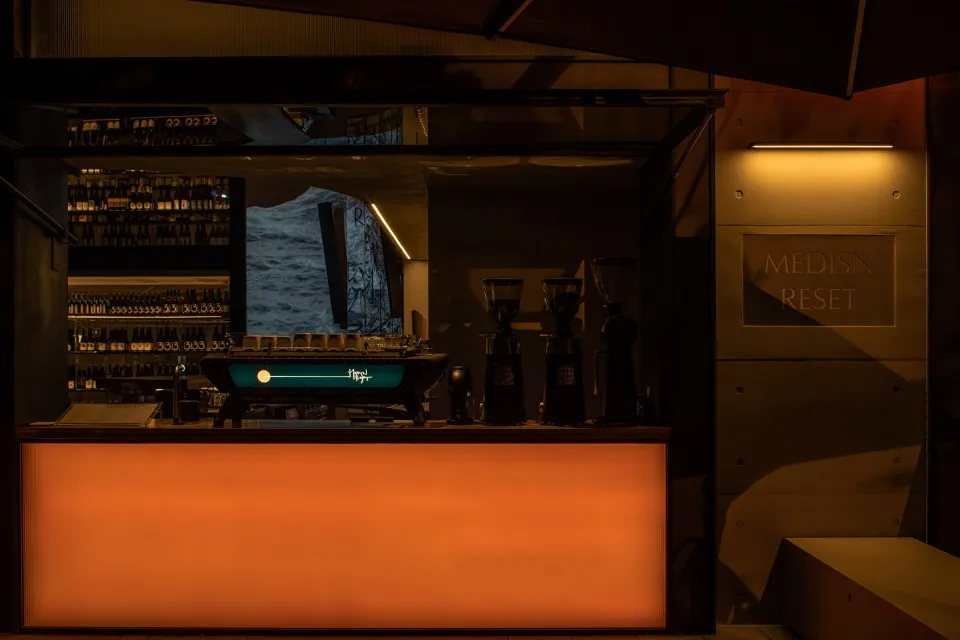 A modern coffee shop with a counter illuminated by warm lighting.