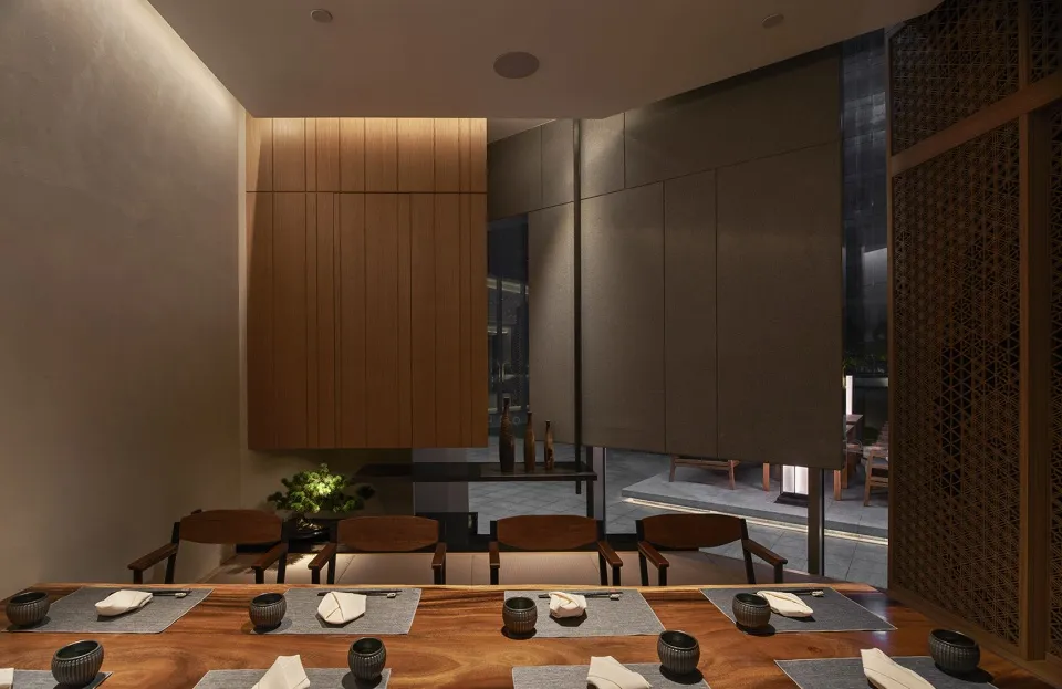 A modern restaurant interior with wooden accents, featuring tables, chairs, and decorative elements.