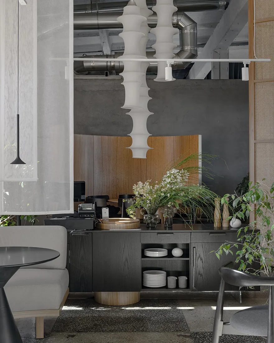 A modern restaurant kitchen featuring concrete walls and ceiling, with a minimalist design and industrial elements.
