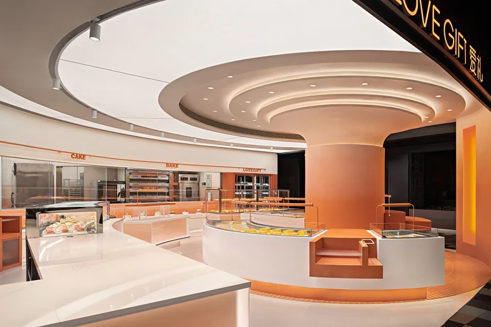 A beautifully modern bakery cafe interior with orange matte walls and white countertop surfaces.