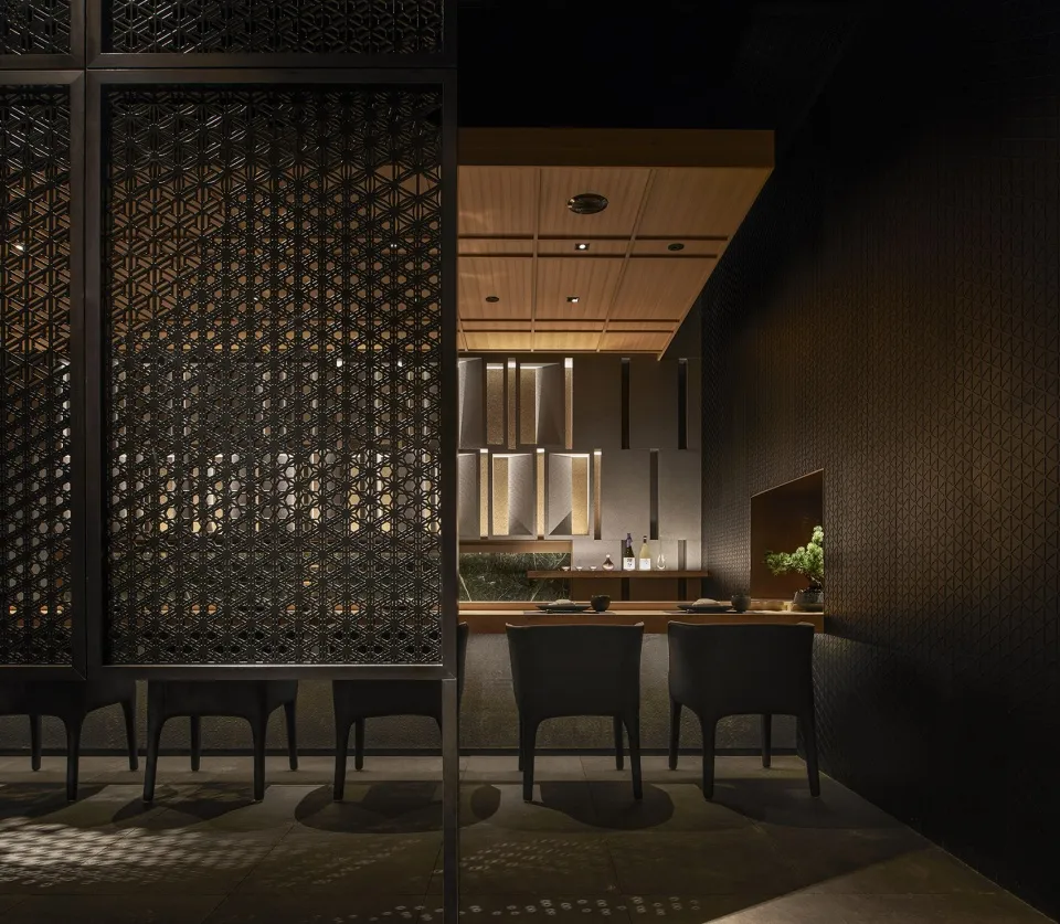 A modern restaurant interior with a black metal frame and metallic patterns on the walls and ceiling.