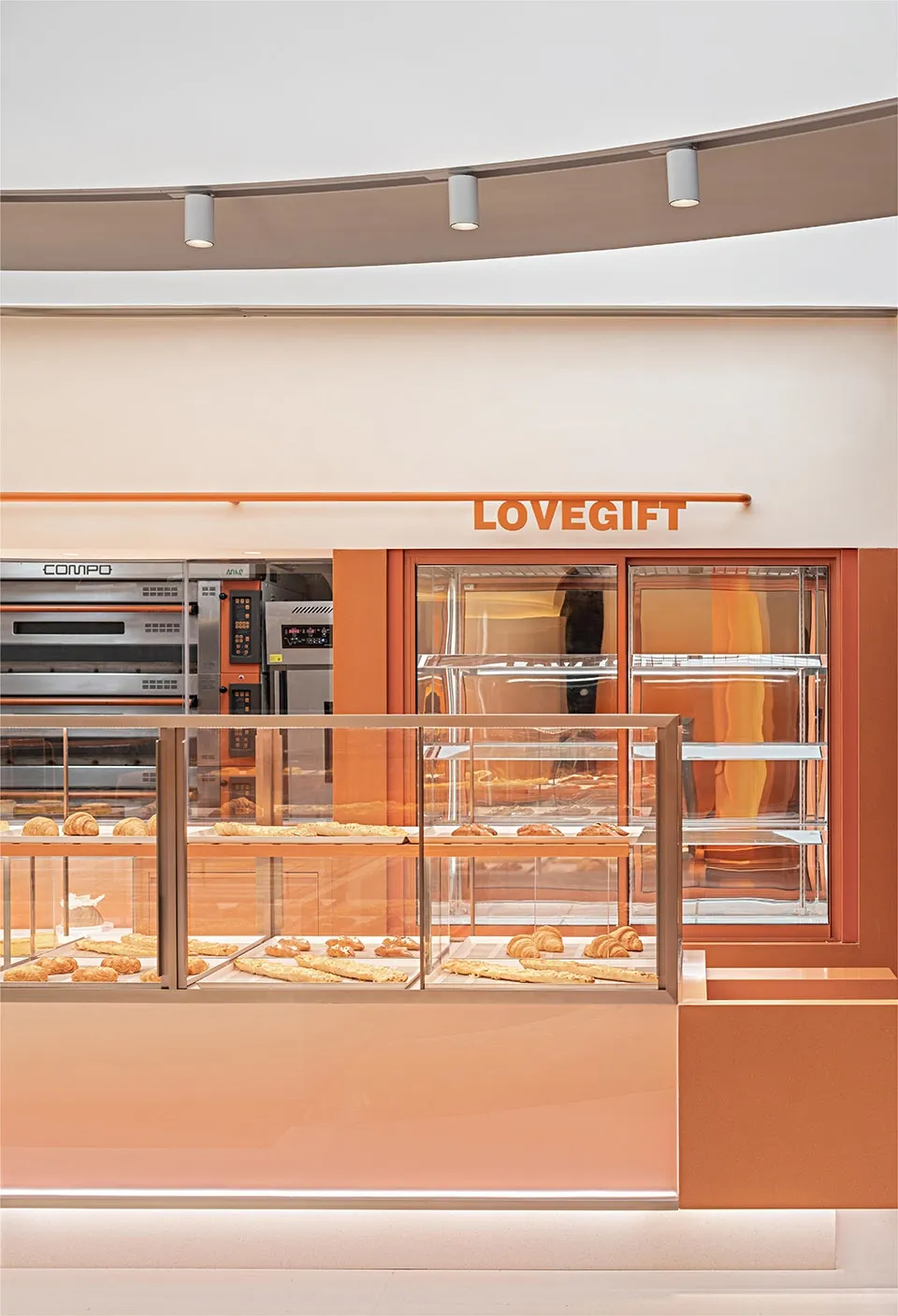 A minimalist bakery interior featuring orange and red acrylic elements.