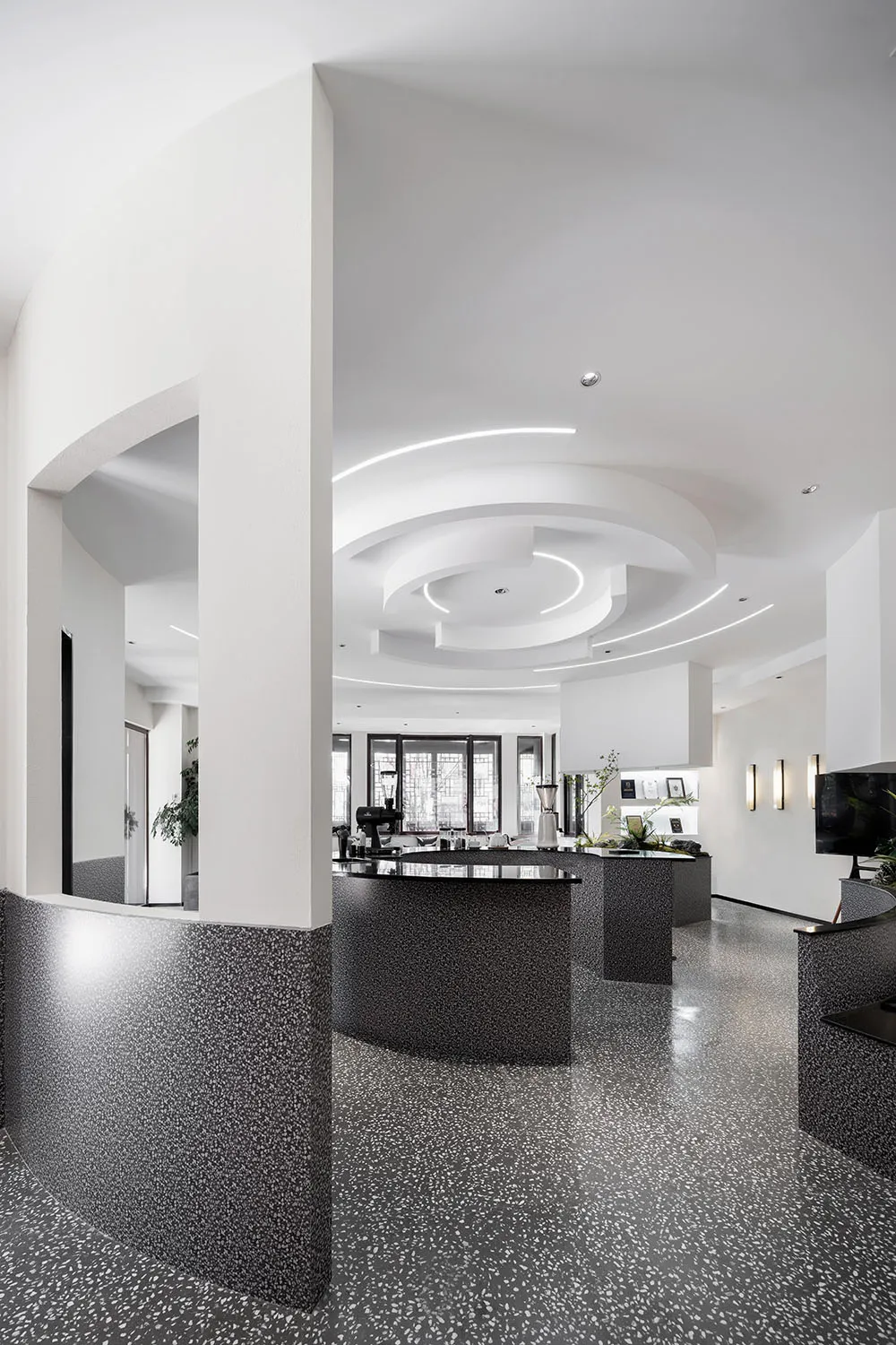 Modern restaurant interior with terrazzo flooring, minimalist design, and sleek black and white decor.