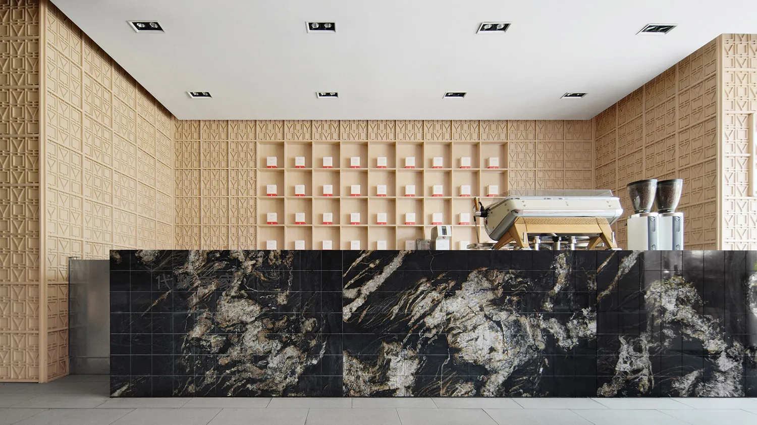 A minimalist industrial-style coffee shop counter showcasing black marble, concrete, and carved wood elements.