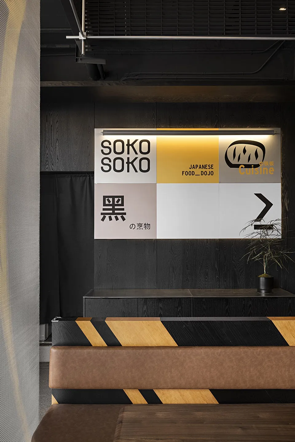 現代餐廳室內以黑色木板牆面裝飾,牆上展示「SOKO SOKO Japanese Food Dojo Cuisine」品牌標誌。