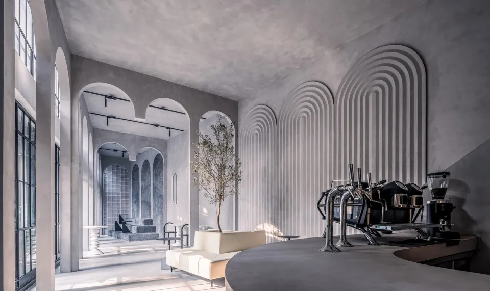 Concrete countertop and industrial-style coffee shop interior with arched windows and arch relief walls.