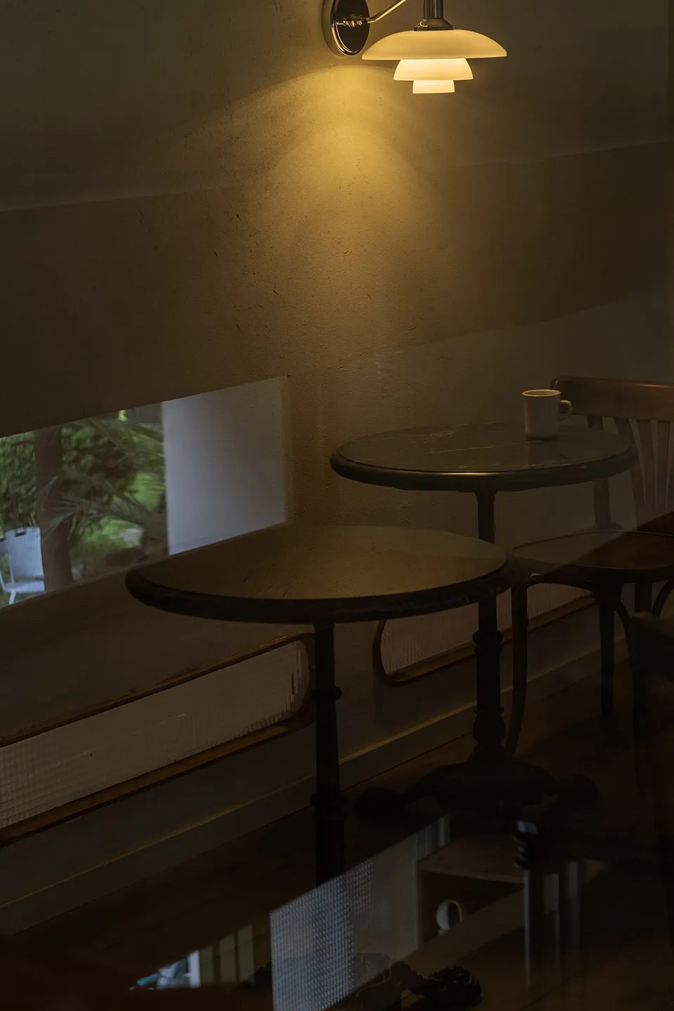 A minimalist cafe interior featuring metal tables under warm lighting.