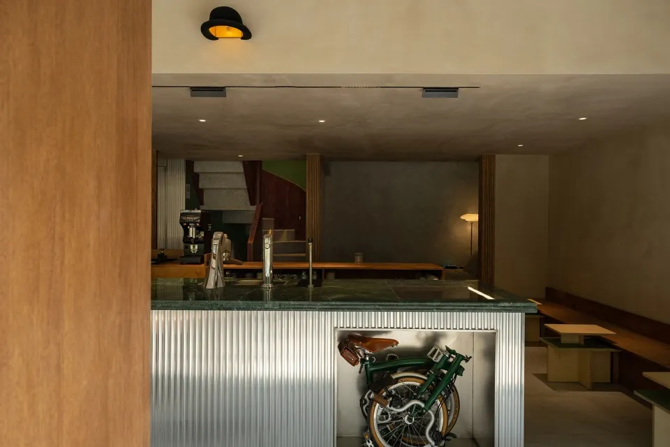 A metallic folding bike is stored under a modern coffee shop's counter.