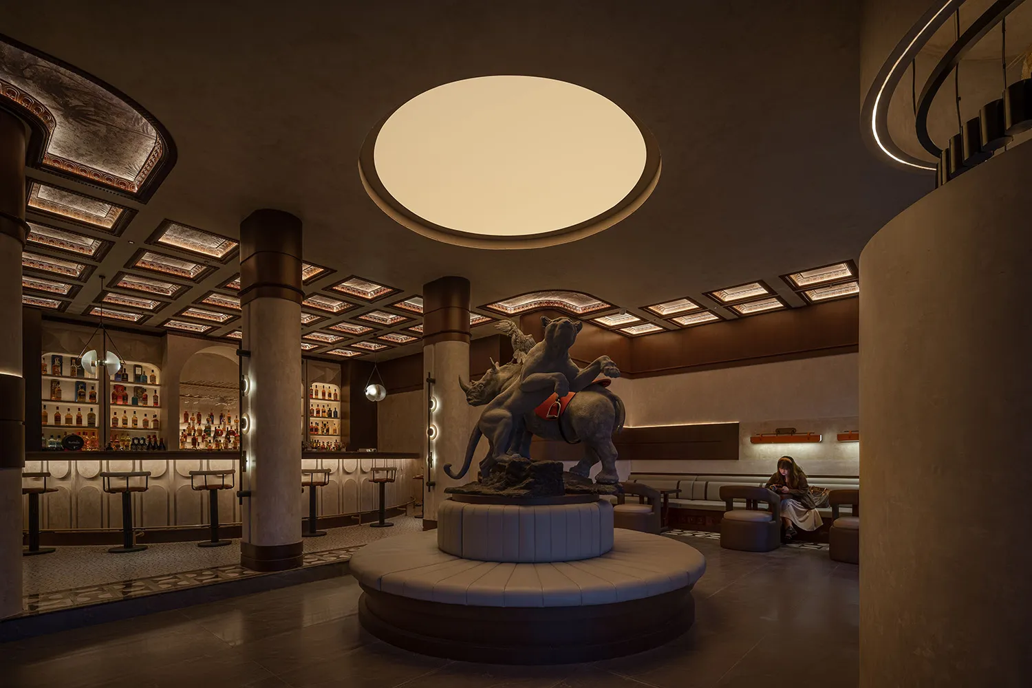 A modern industrial restaurant interior with a concrete ceiling and floor, featuring a statue of a lion and lioness riding a 
