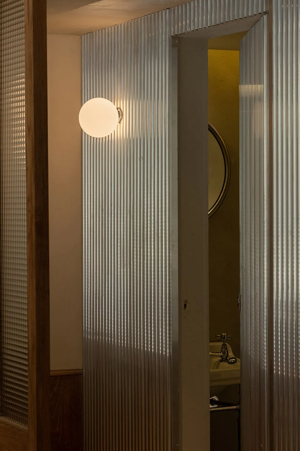 Minimalist interior design featuring a metal wall structure with a round wall-mounted light fixture.