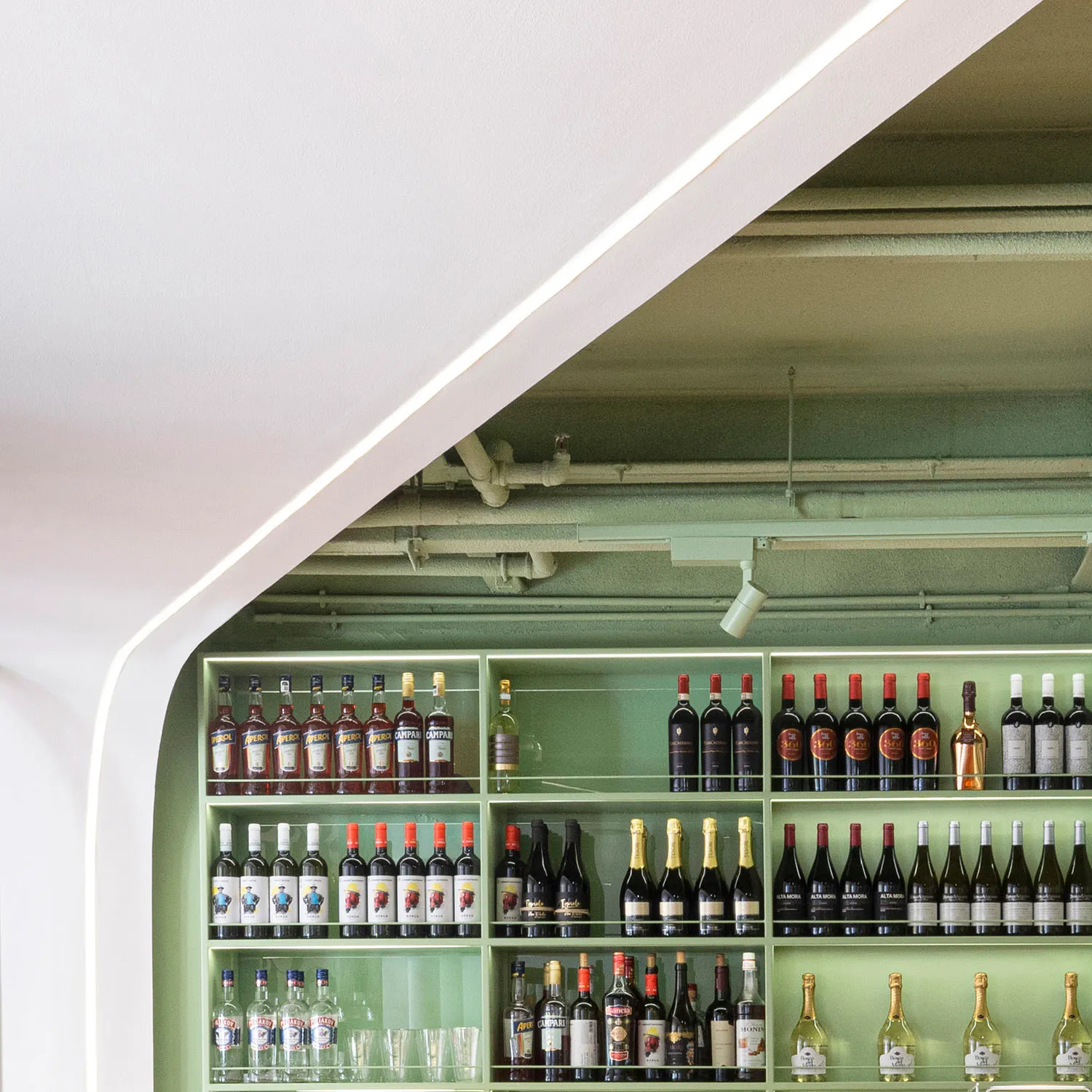 A modern green bar shelf filled with various drinks and glasses.