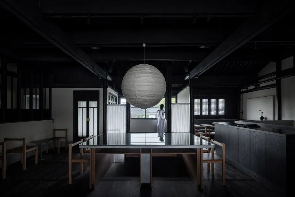 Contemporary restaurant interior with dark wooden furniture and a large spherical light fixture.